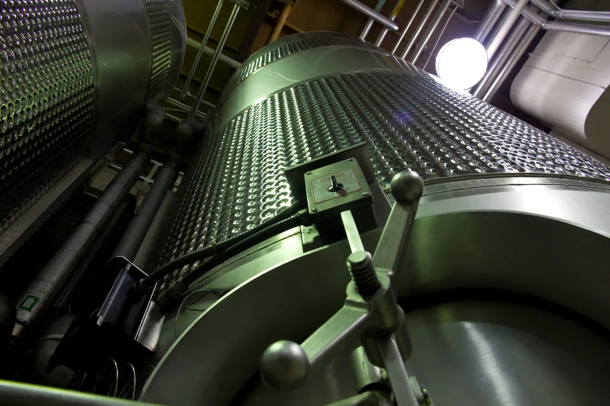 Low-angle view of stainless-steel process tanks and piping in an industrial production facility